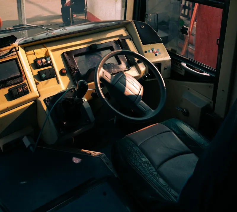 Puesto de conductor de un autobús: volante, salpicadero con botones y asiento.